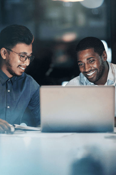 Homens sorrindo olhando um notebook.