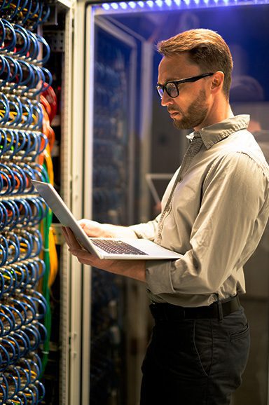 Homem com notebook trabalhando no datacenter