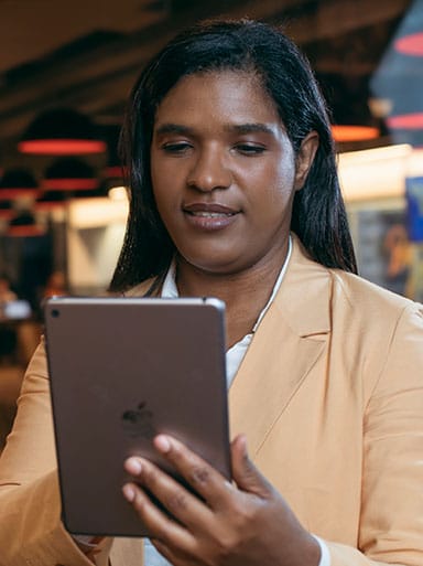 Mulher negra, sorrindo e olhando para o tablet