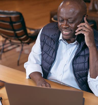 Homem negro trabalhando com celular e notebook