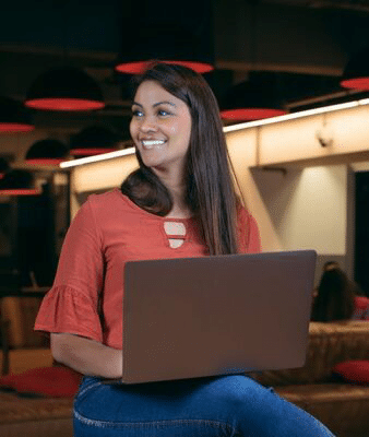 Mulher sentada com notebook olhando para o lado.